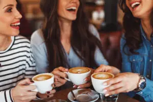 Women gathered around the table enjoying catching up over coffee.